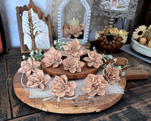 Blush taupe wood flowers laid out on a vintage bread board in a rustic cottage table setting.